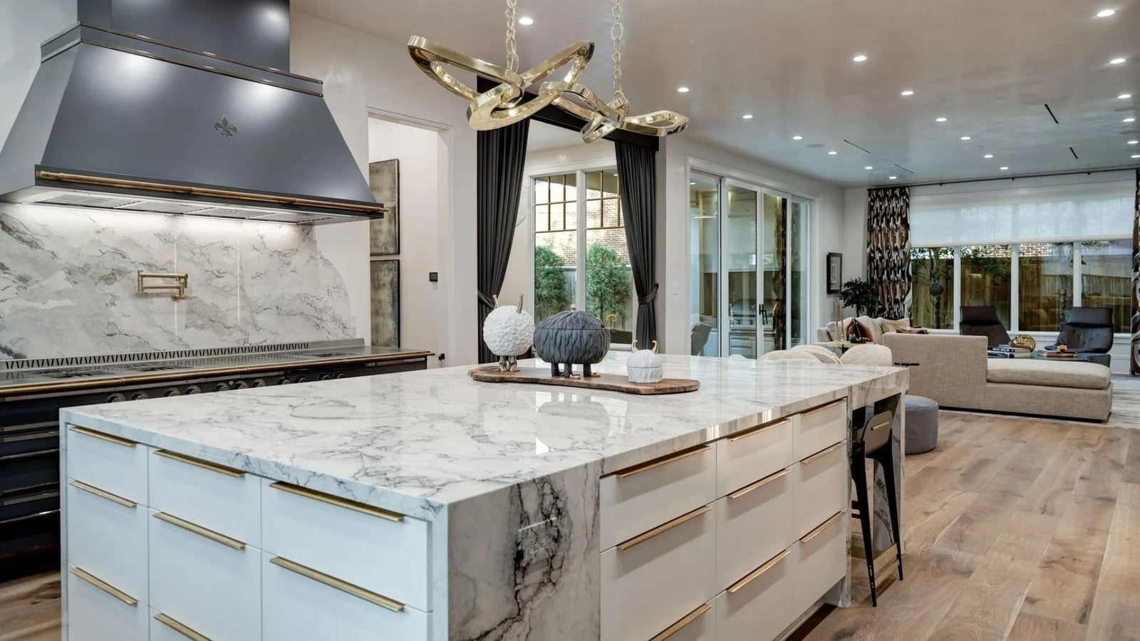 Open-plan kitchen with a matte range and hood anchoring a clear sightline into the living room